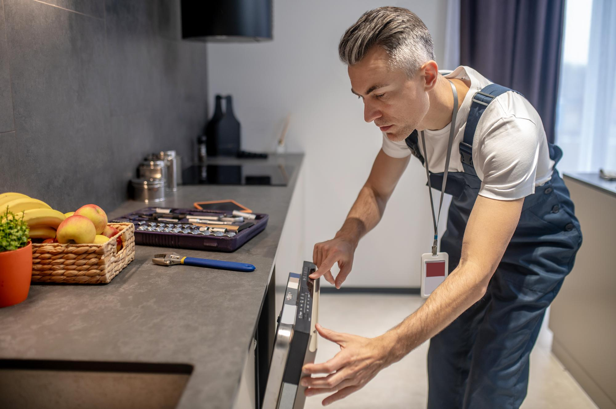 man-looking-information-control-panel-dishwasher